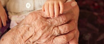 Infant holding an elderly person's hand