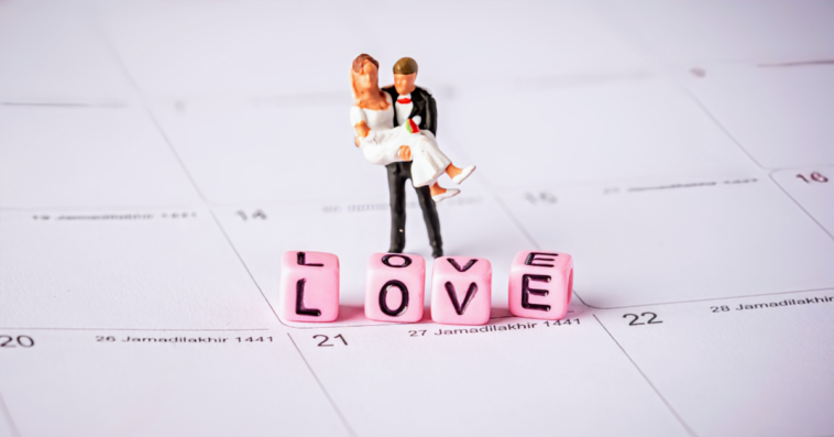 miniature bride and groom on calendar with word "love" in pink blocks