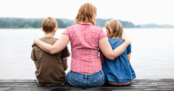 mother seated on dock between two children
