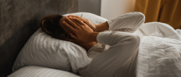 woman laying in bed with hands covering face