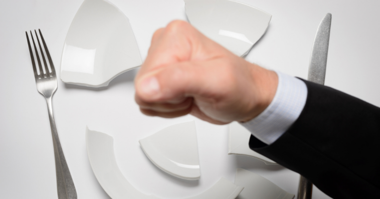man smashing dinner plate with fist