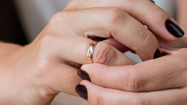woman adjusts gold wedding band on her finger