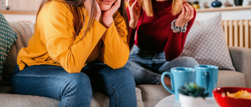 two adult women seated on couch arguing