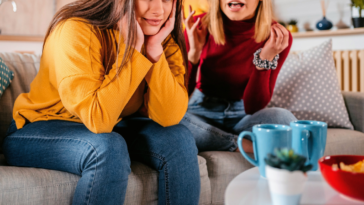 two adult women seated on couch arguing