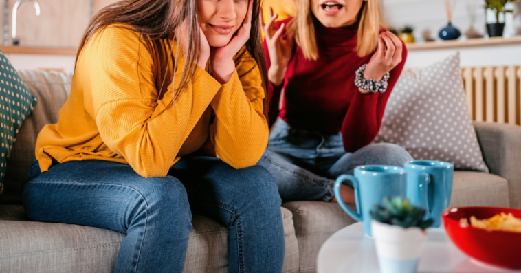 two adult women seated on couch arguing