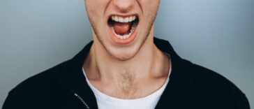 Shouting young man against a blue-gray backdrop.