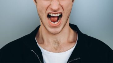 Shouting young man against a blue-gray backdrop.