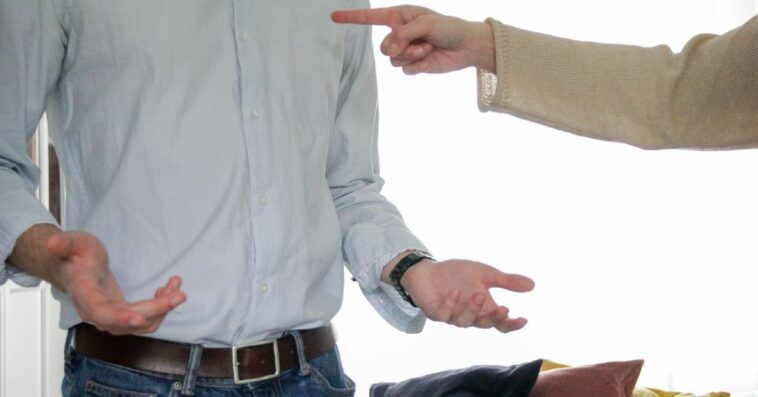 A headless, mid-shot of two men in a heated moment. One man is pointing his finger at the other.