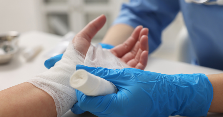 A man getting his hand wrapped in gauze
