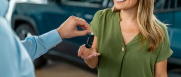 Smiling woman receiving her car keys in an auto saloon.