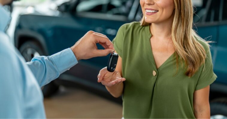 Smiling woman receiving her car keys in an auto saloon.