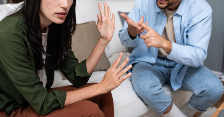 A couple sitting on the sofa having an argument.