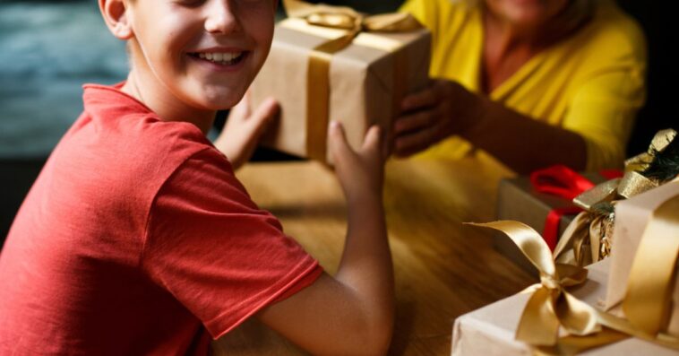 Cheerful boy, elementary age is getting presents from his granny.