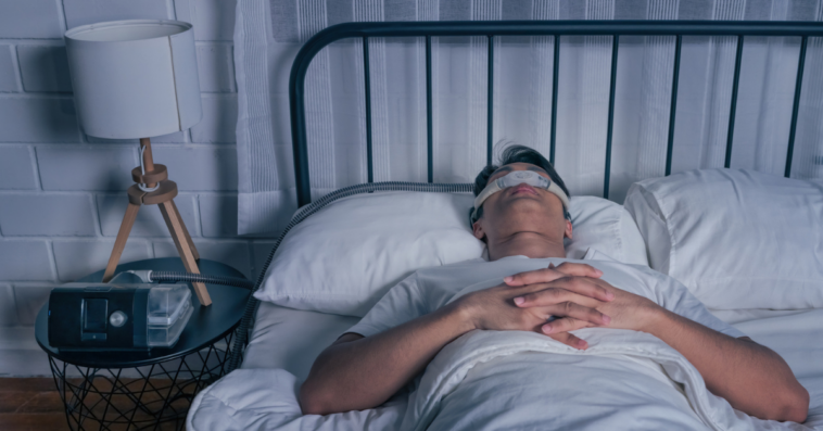 A man sleeping with a CPAP machine attached to his nose.
