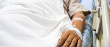 A man lying in a hospital bed hooked up to tubes.