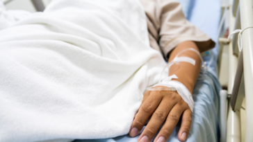 A man lying in a hospital bed hooked up to tubes.