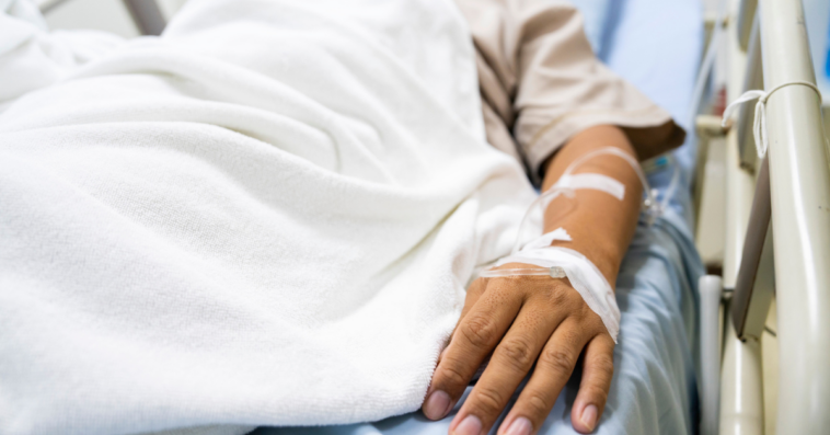 A man lying in a hospital bed hooked up to tubes.