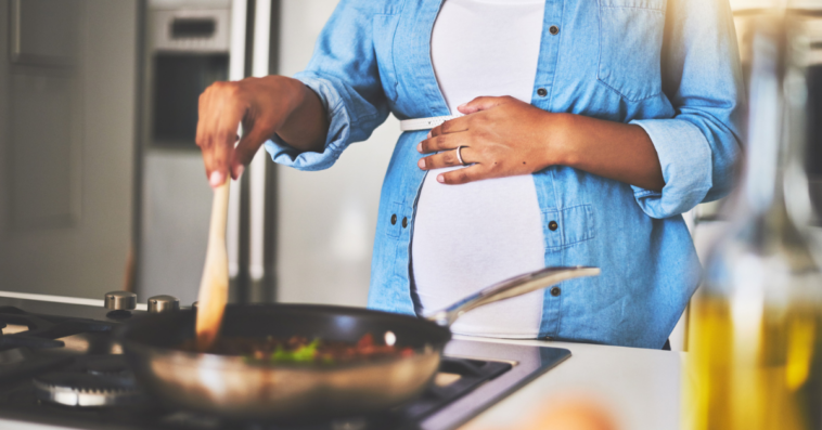 A pregnant woman cooking at a stovetop.