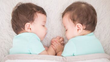 Newborn beautiful baby twins sleeping with pacifier. Closeup portrait.