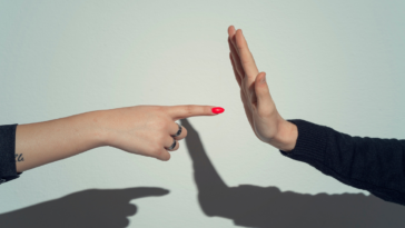 A woman pointing her finger at a man's palm.