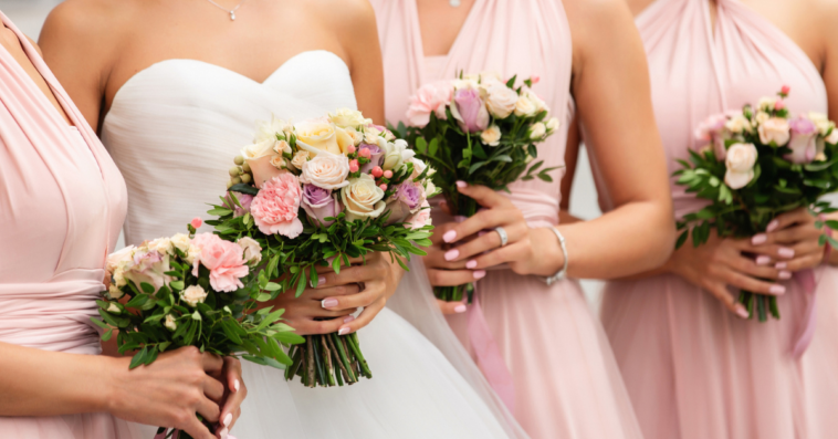 A bride surrounded by bridesmaids in pink bridesmaids dresses.