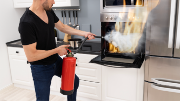 A putting out an oven fire with a fire extinguisher.