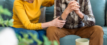concerned older couple seated on couch