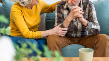 concerned older couple seated on couch