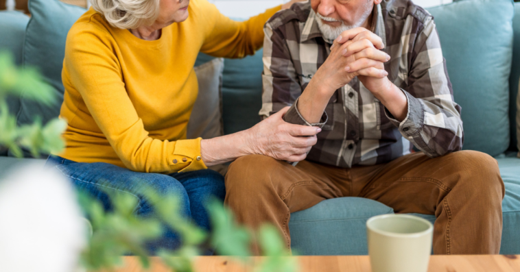 concerned older couple seated on couch