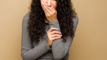 young woman covering her mouth to smother laughter