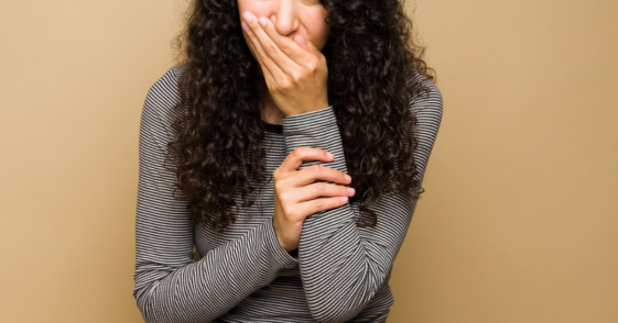 young woman covering her mouth to smother laughter