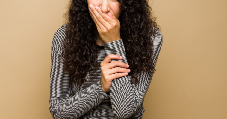 young woman covering her mouth to smother laughter