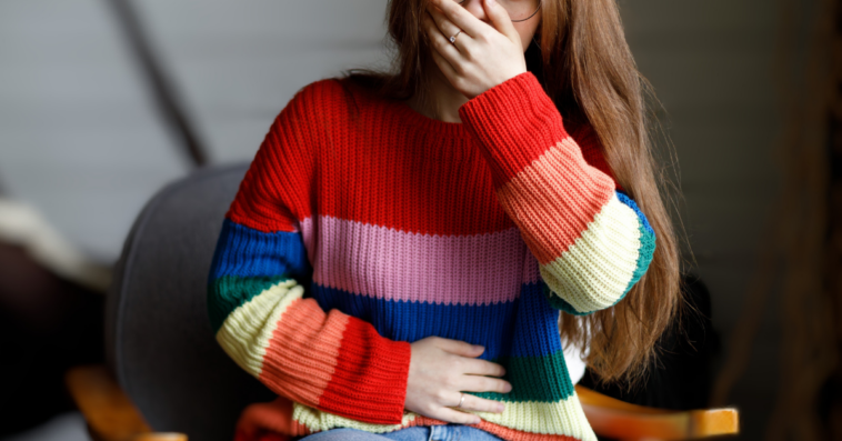 woman clutches mouth and stomach
