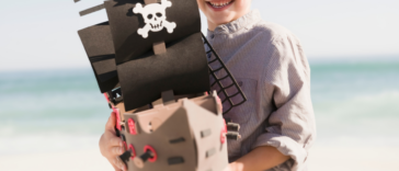 child in pirate costume holding toy ship