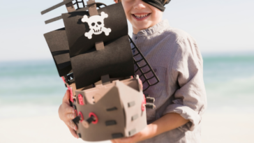 child in pirate costume holding toy ship