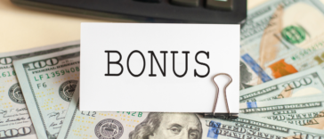 A sign saying "bonus" on top of a pile of cash.