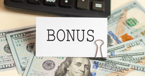 A sign saying "bonus" on top of a pile of cash.