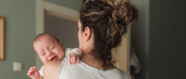 Newborn baby crying when being held in mother's arms.