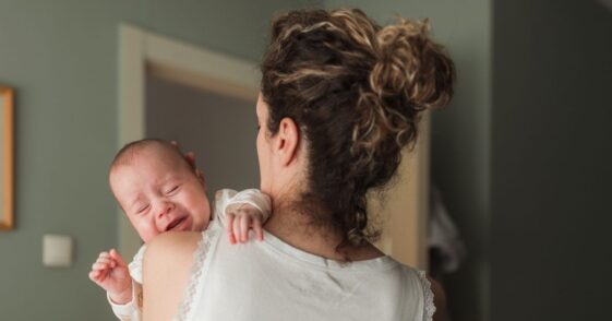 Newborn baby crying when being held in mother's arms.