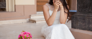 A bride sitting on steps crying into her hands.