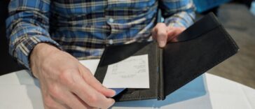 Close-up of unrecognizable man reviewing check at restaurant while placing credit card in holder.