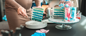 A pregnant woman cutting into a blue gender reveal cake.