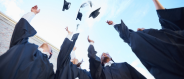 A group of gradating students throwing their graduation caps in the air.