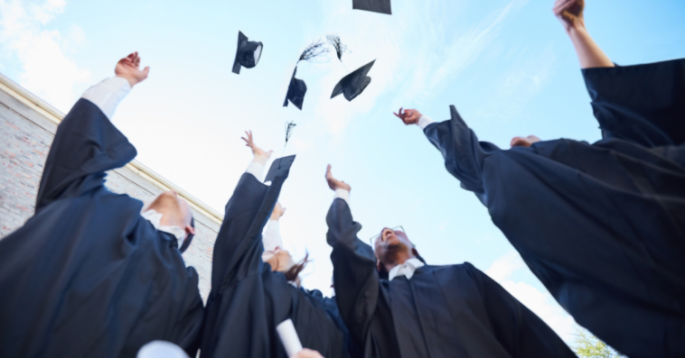 A group of gradating students throwing their graduation caps in the air.