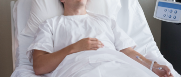 A man lying down in a hospital bed attached to an IV.