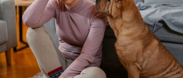 Sad young woman sitting on the floor with her shar-pei dog at home and sulking.