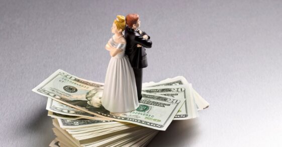 Wedding figurine couple back to back on a pile of Dollars.