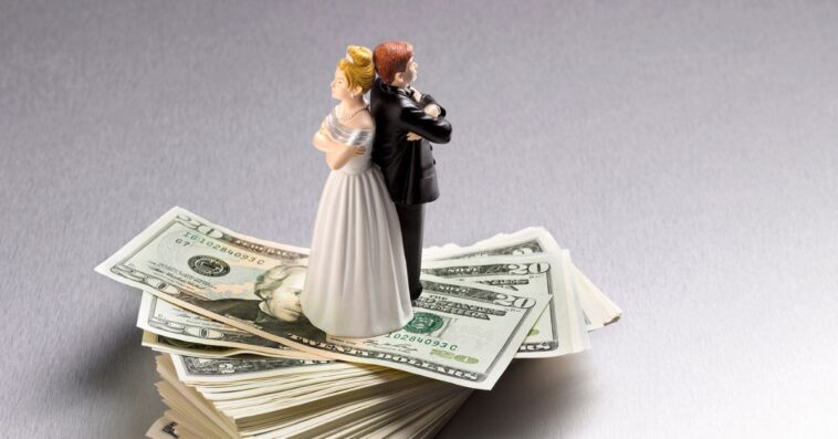 Wedding figurine couple back to back on a pile of Dollars.