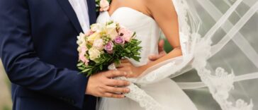 Bride in beautiful white wedding dress with bouquet and elegant groom in blue suit at happy wedding day.