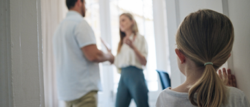 Small child looking in on parents arguing